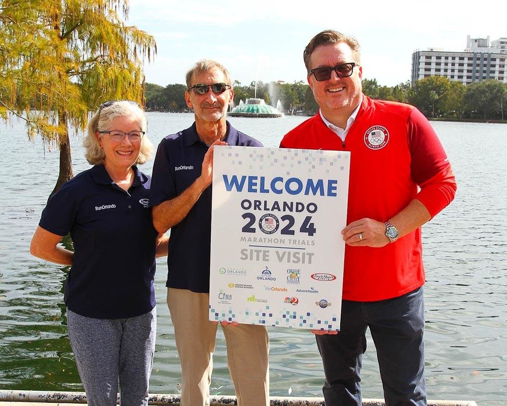 three people with sign welcoming the orlando 2024 marathon trials